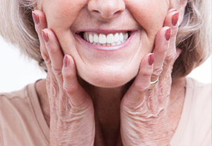 Woman smiling with hands on her chin after getting new complete dentures from Smile Family Dentistry in Concord, CA 